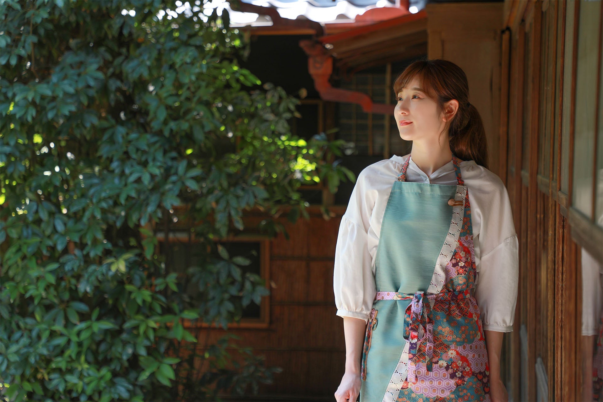 Japanese woman wearing a handcrafted apron in a Japanese style house's garden